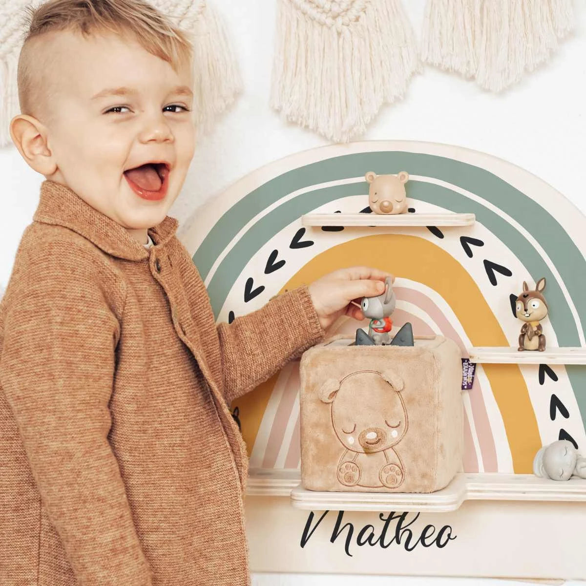 Junge steht lachend vor buntem Tonie Regal und lacht in die Kamera