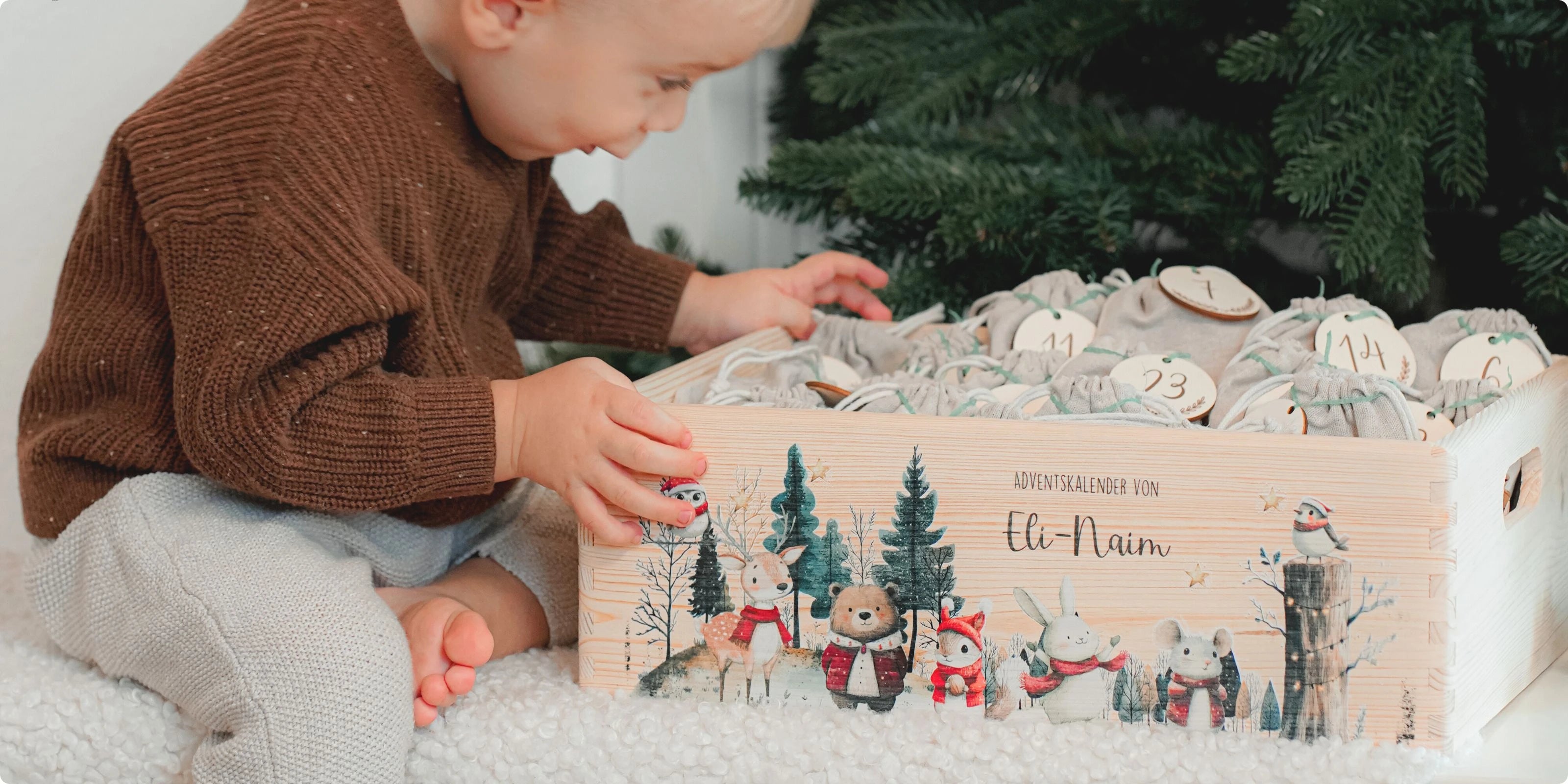 Kind im braunen Strickpullover öffnet personalisierten Adventskalender "Eli-Naim" mit winterlicher Waldszene und niedlichen Tieren mit roten Schals. Die grauen Stoffbeutel mit Nummern bieten tägliche Überraschungen für die Adventszeit. Perfektes Weihnachtsaccessoire für Kinder, um die Vorweihnachtszeit zu genießen.WiederholenClaude kann Fehler machen. Bitte überprüfen Sie die Antworten.