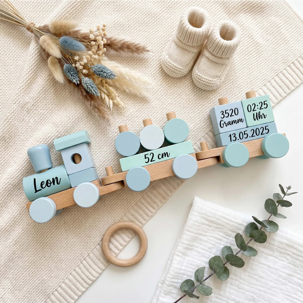Holzzug personalisiert in Blau als Flatlay mit Babyschuhen