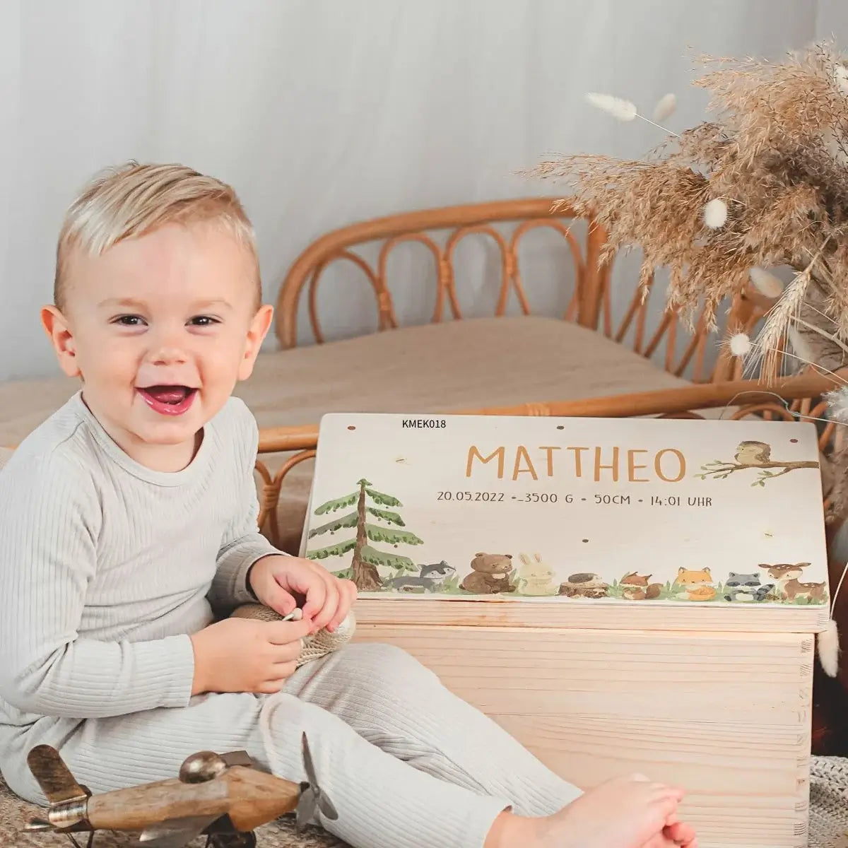Personalisierte Erinnerungsbox aus Holz mit Namen Mattheo und Geburtsdaten, Waldtier-Motiv, Kind zeigt Freude über personalisiertes Geschenk zur Geburt
