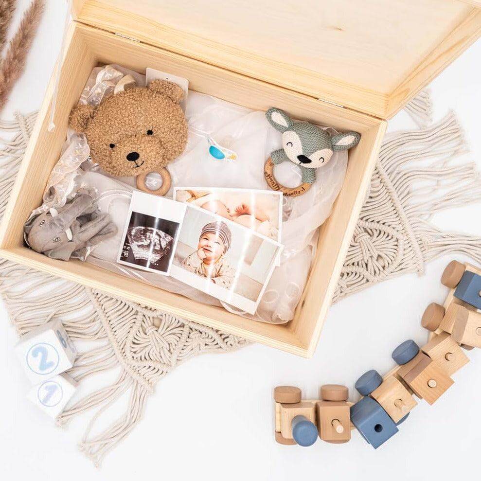 Kleinkind berührt liebevoll seine personalisierte Regenbogen-Erinnerungsbox aus Holz mit Namen Layla als besonderes Geburtsgeschenk
